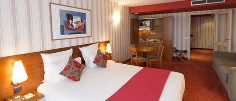 A hotel room with a bed, bedside lamp, telephone, and a painting on the wall.