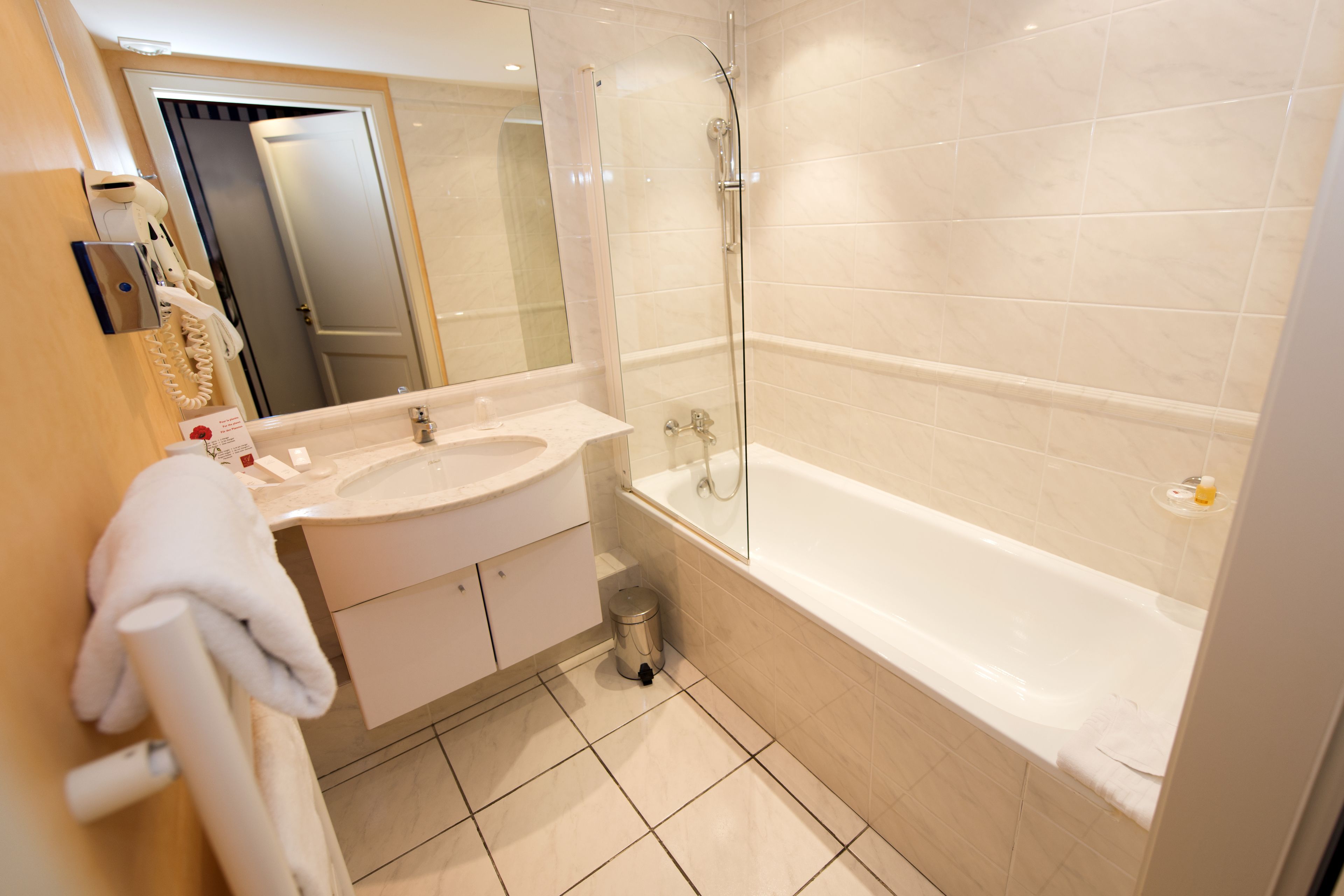 A modern bathroom with a large bathtub, a glass-enclosed shower, and a vanity with a sink and mirror.