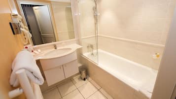 A modern bathroom with a large bathtub, a glass-enclosed shower, and a vanity with a sink and mirror.