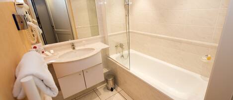 A modern bathroom with a large bathtub, a glass-enclosed shower, and a vanity with a sink and mirror.