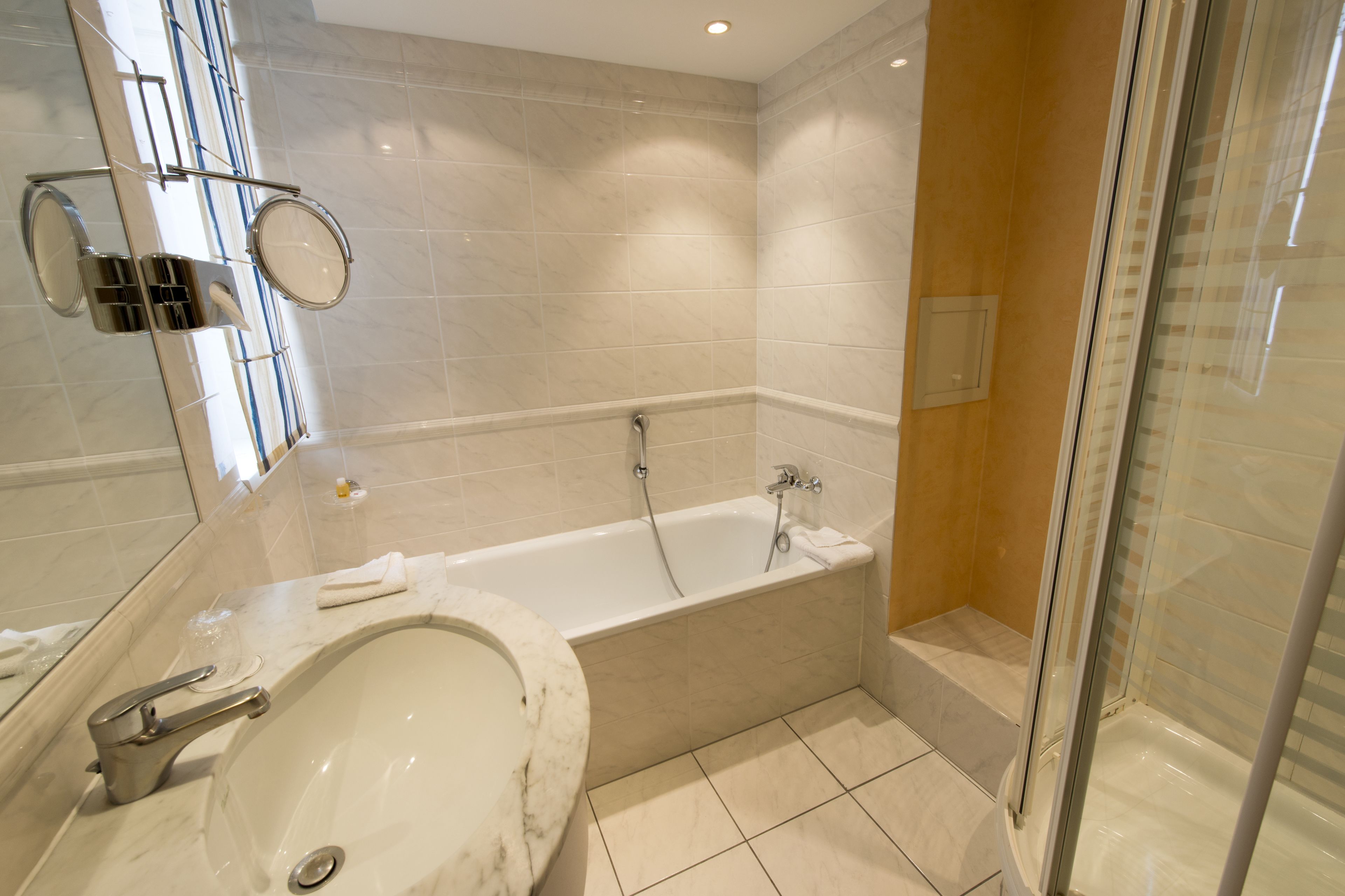 A modern bathroom with a bathtub, a sink, and a glass shower enclosure.