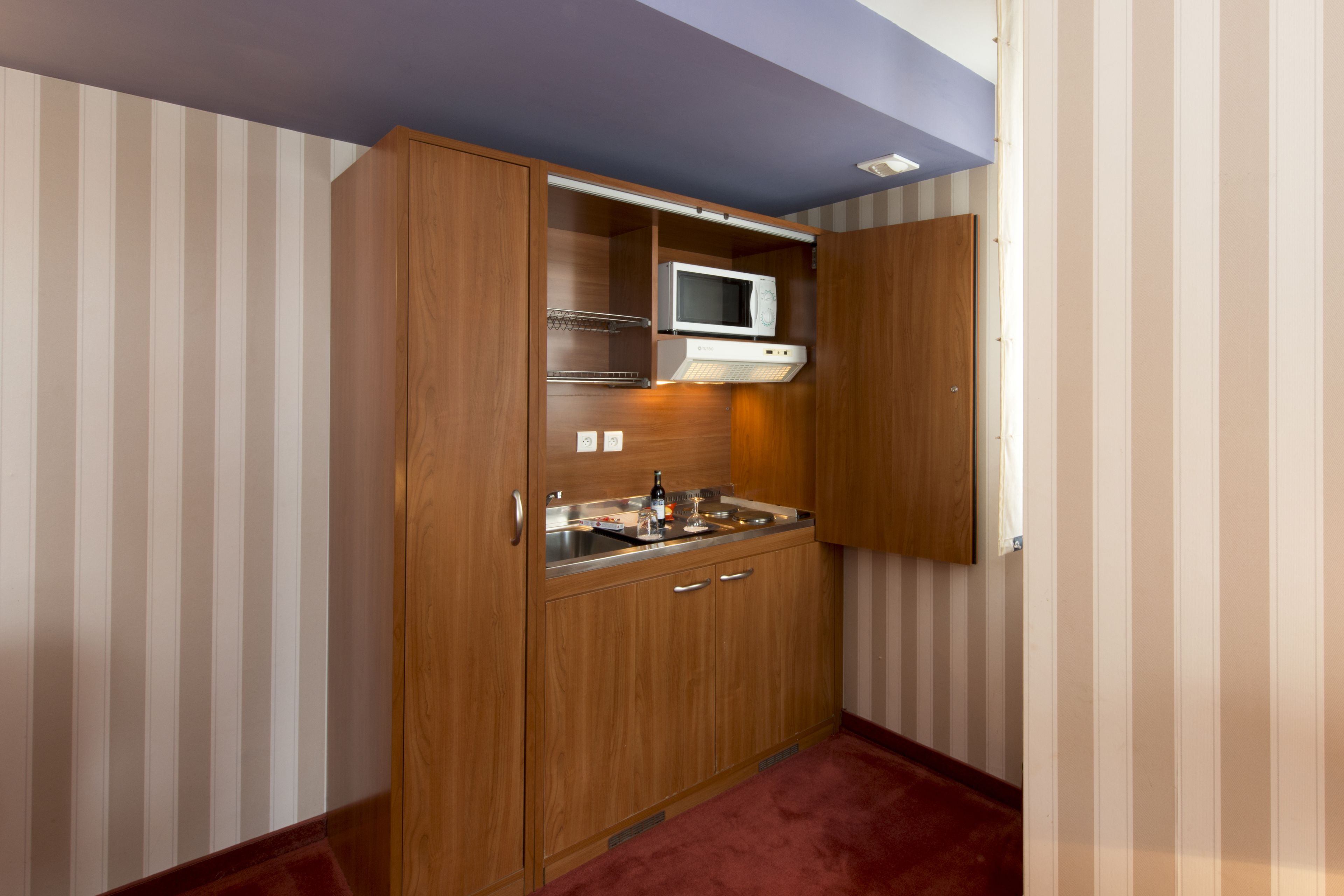 A compact kitchen with wooden cabinets, a microwave, and a sink.