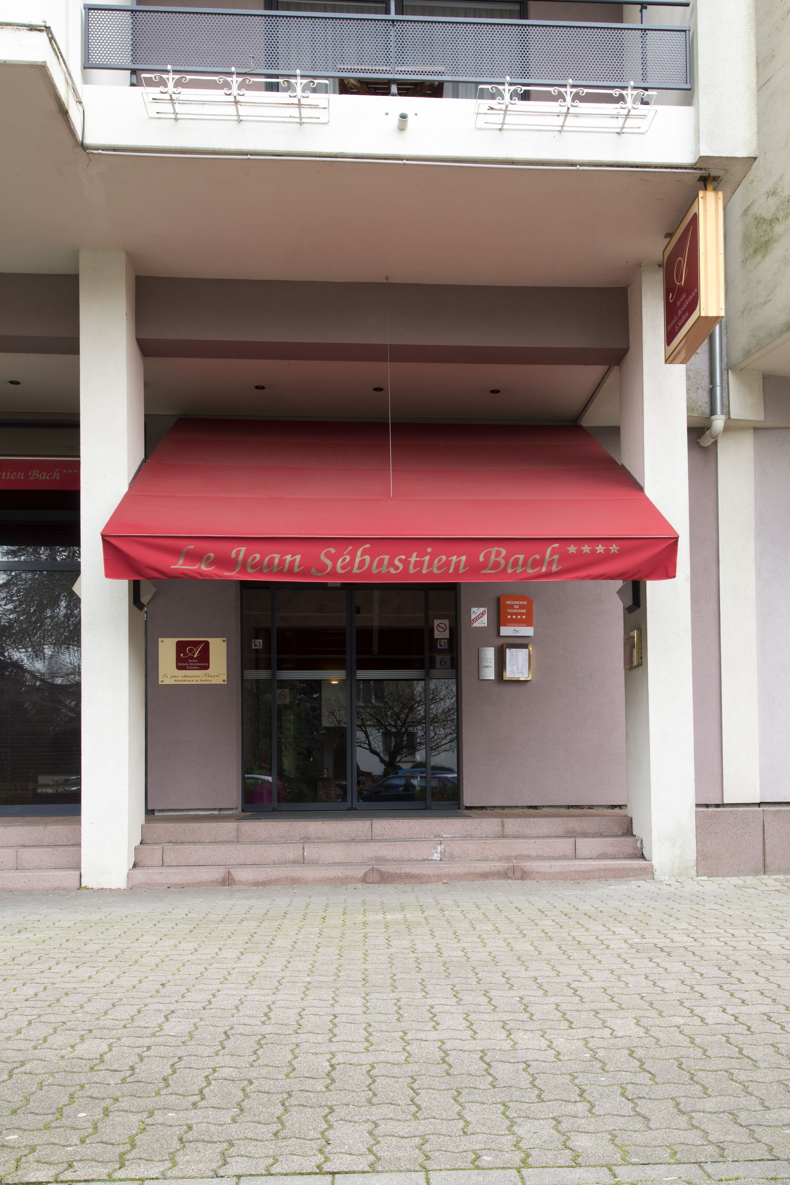 A building with a red awning and a sign reading "Le Jean Sébastien Bach."