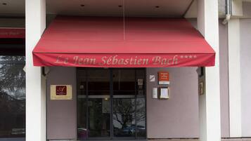 A building with a red awning and a sign reading "Le Jean Sébastien Bach."