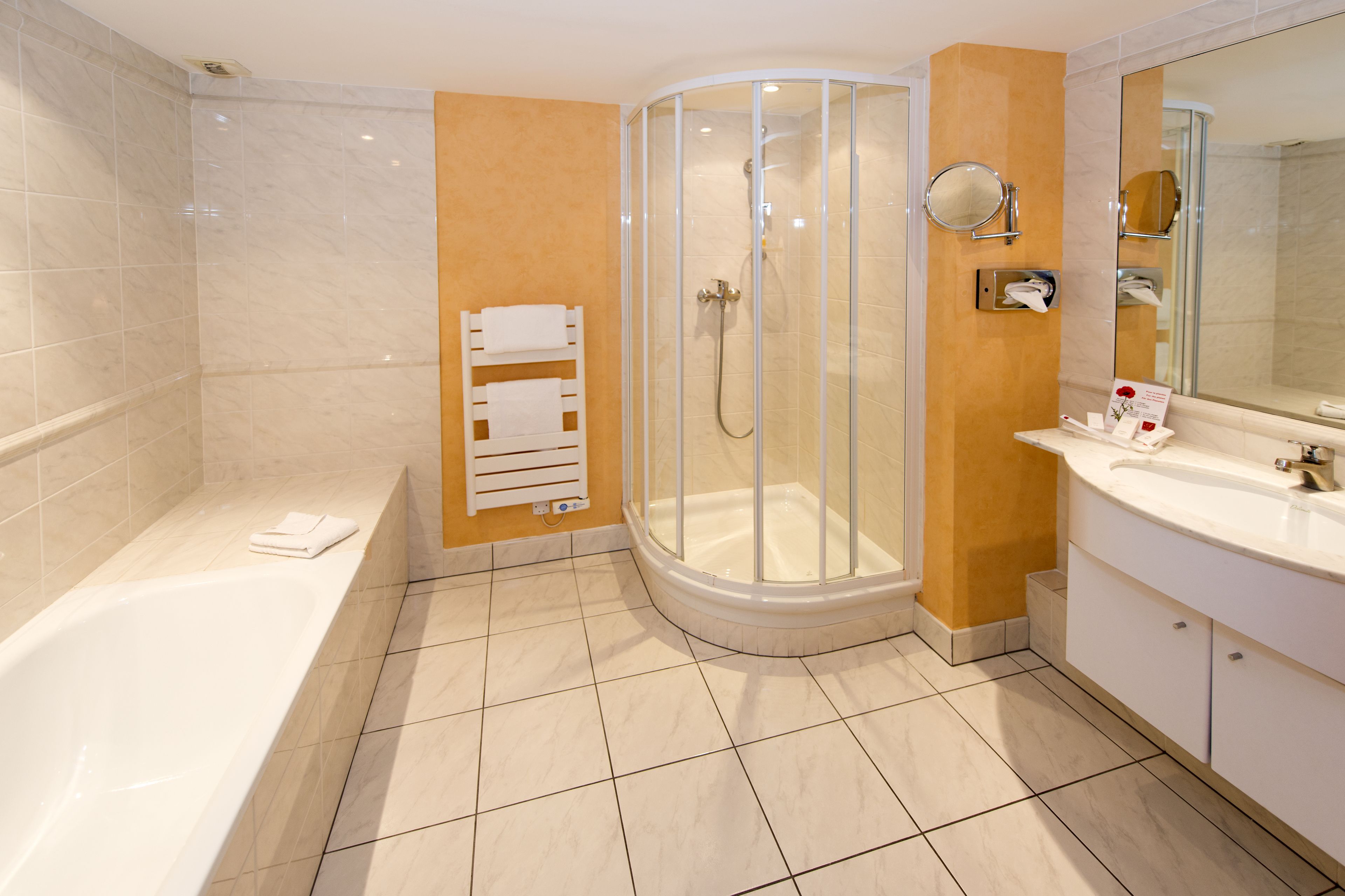 Ein modernes Badezimmer mit Badewanne, einer Dusche mit Glasabtrennung und einem Waschtisch mit Spiegel.