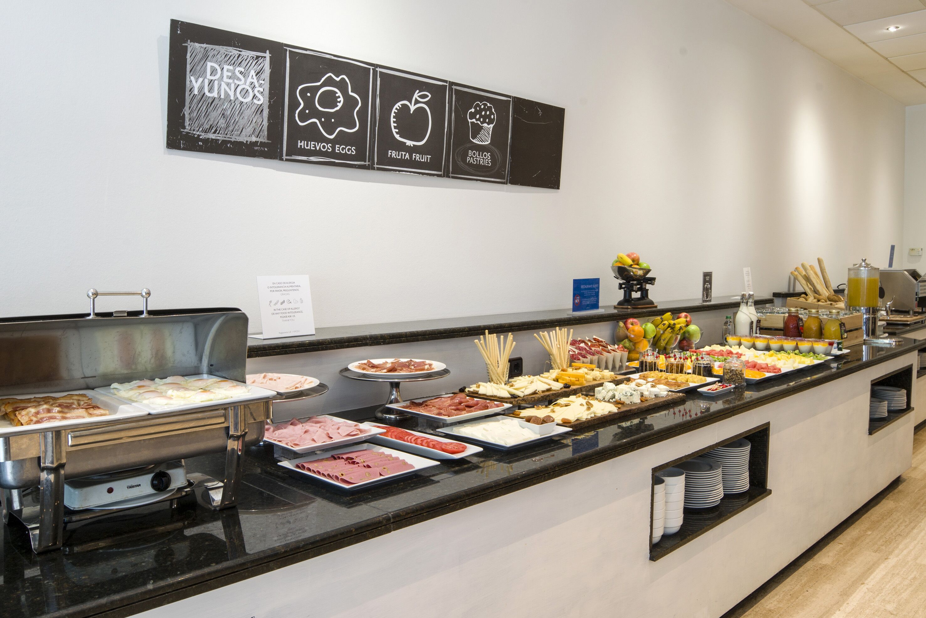 A buffet with various food options and a sign above indicating breakfast items.