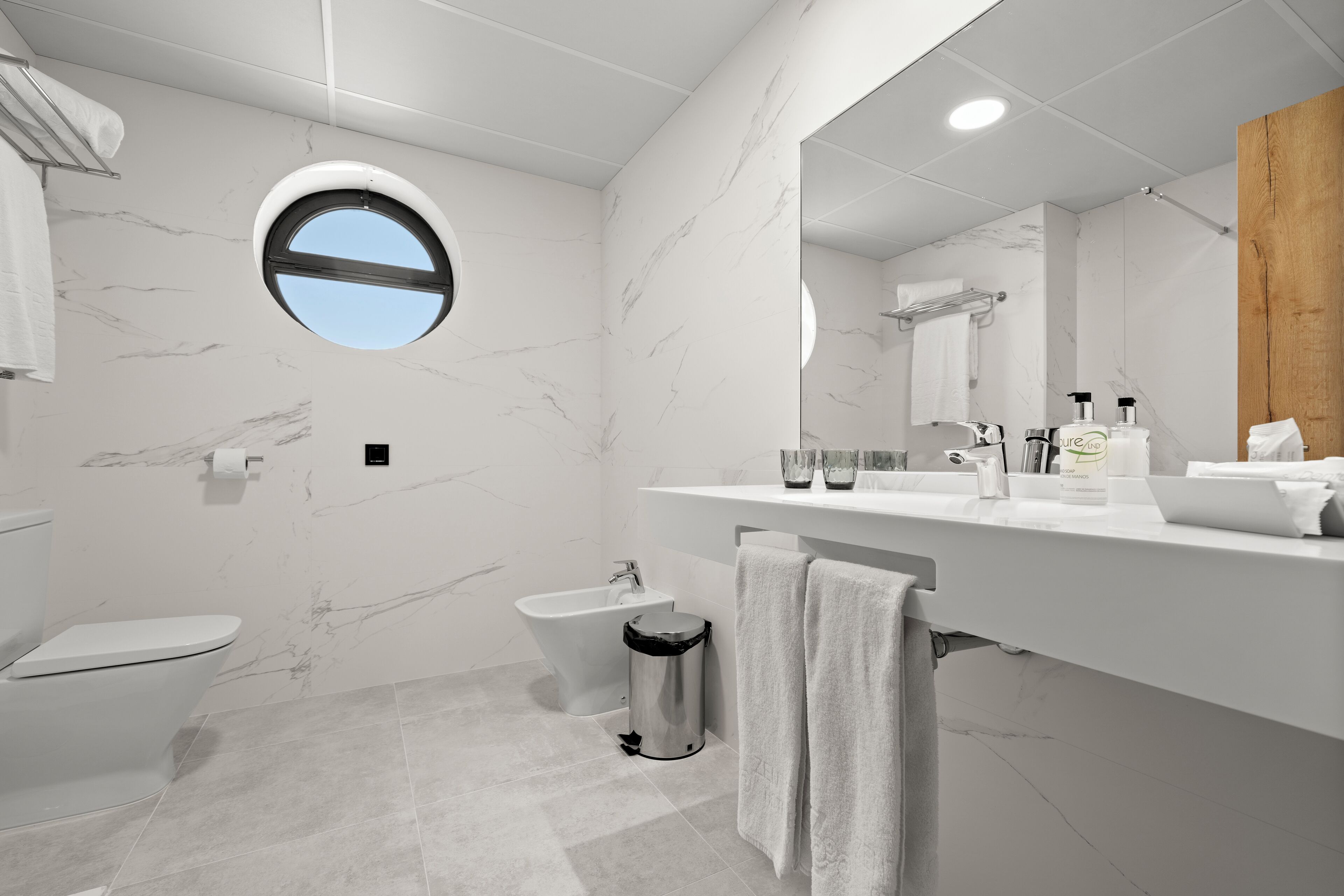 Een moderne badkamer met toilet, bidet en een wastafel met spiegel.