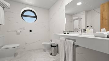 Een moderne badkamer met toilet, bidet en een wastafel met spiegel.