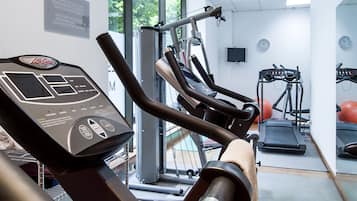 Un gimnasio con cintas de correr, elípticas y pelotas de ejercicio.