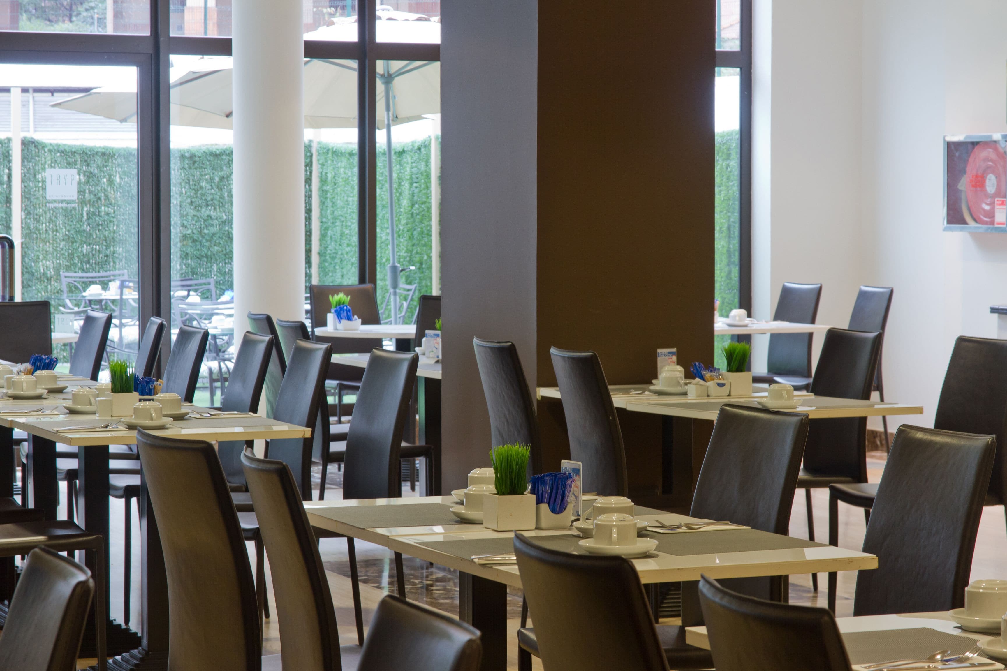 Un espace repas avec des tables dressées, des chaises et une vue sur l’extérieur.