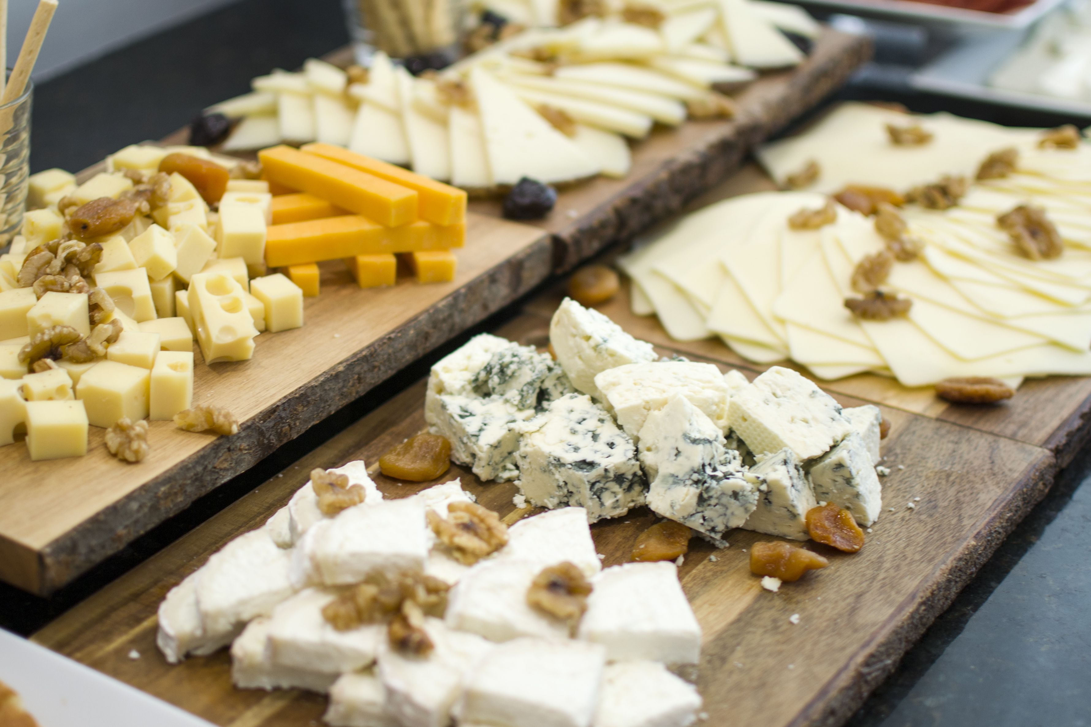 A variety of cheeses and nuts on wooden boards.