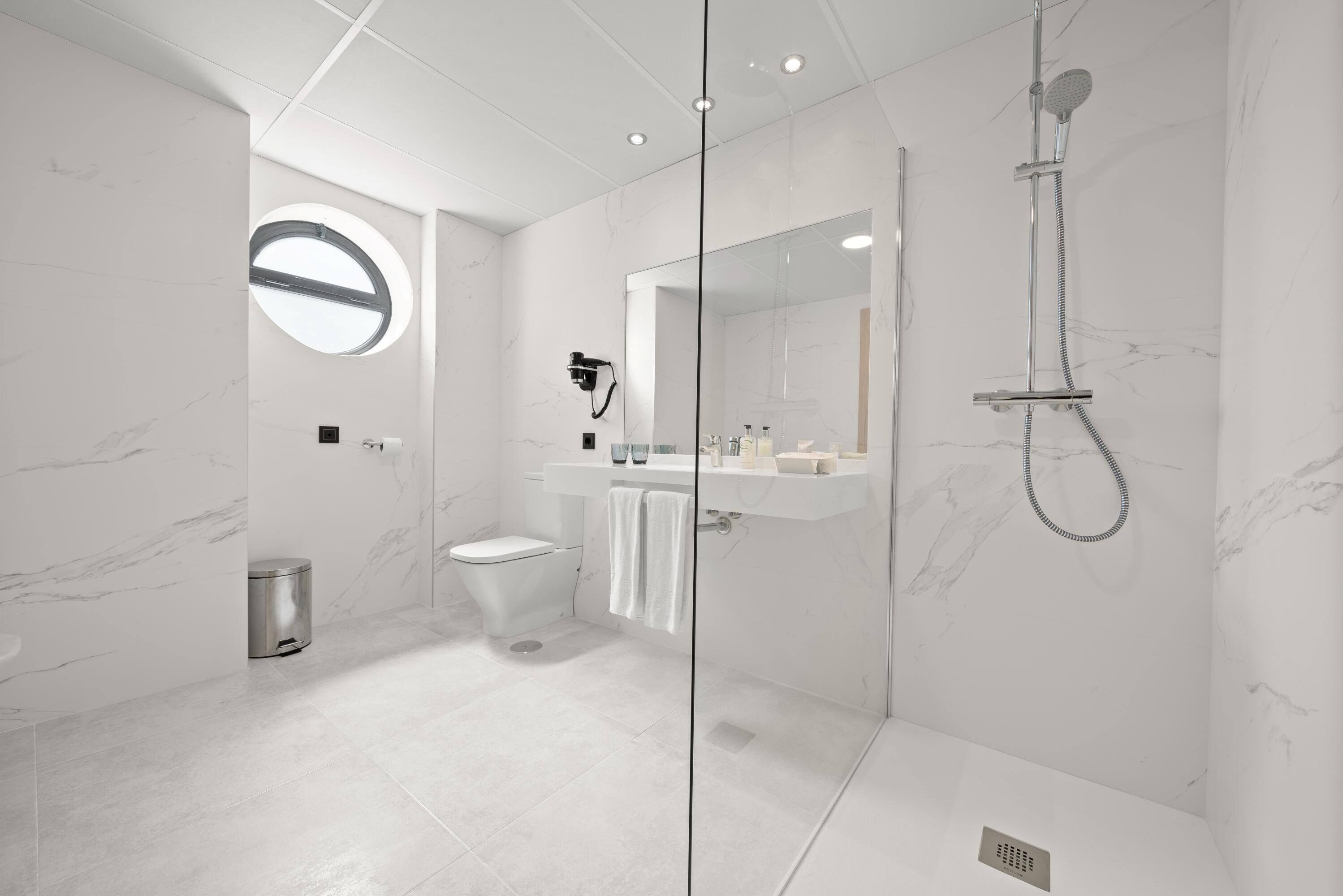 A modern bathroom with a glass-enclosed shower, a toilet, and a sink with a mirror above it.