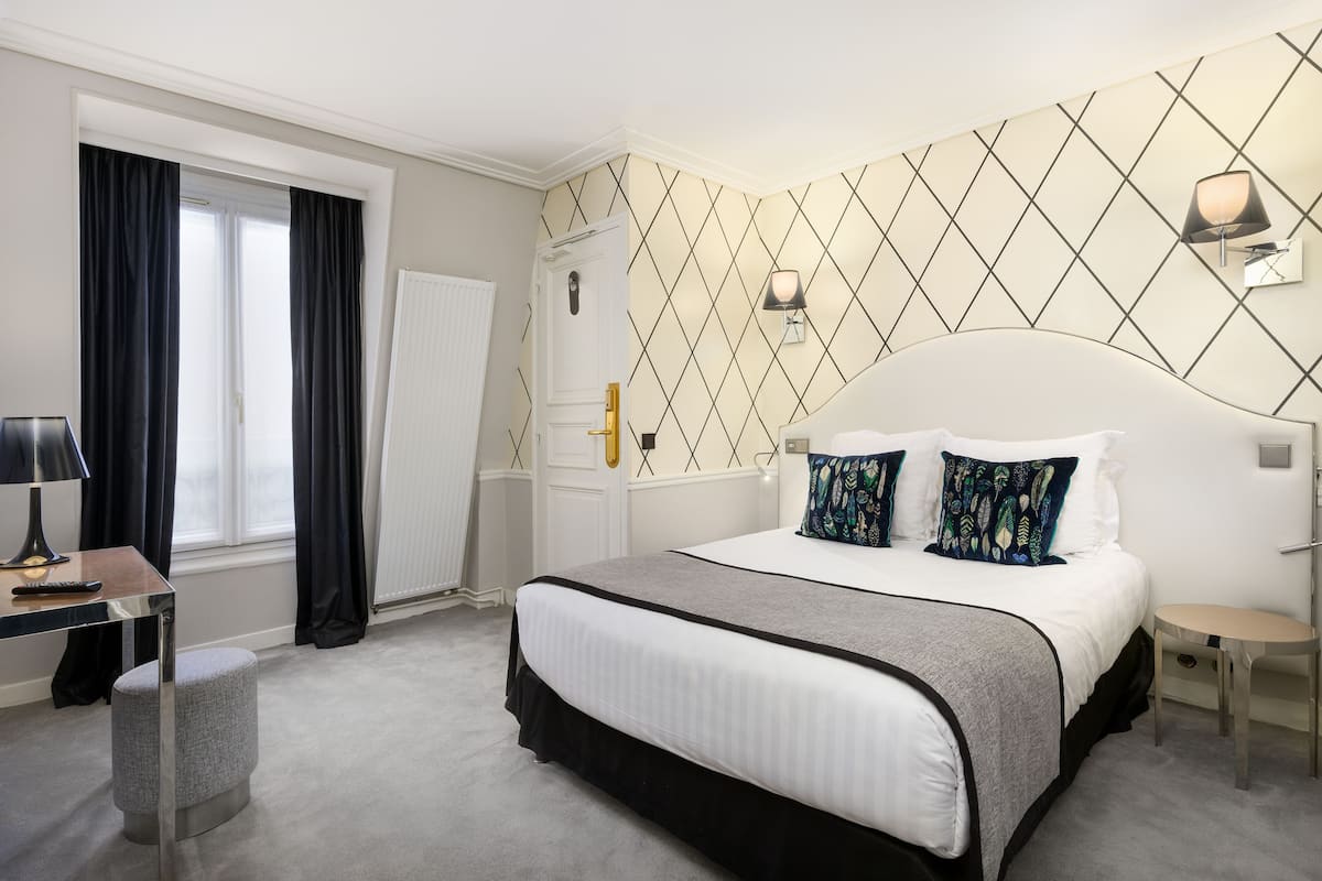 Ein modernes Hotelzimmer mit einem großen Bett, einem Schreibtisch und einem Stuhl.
