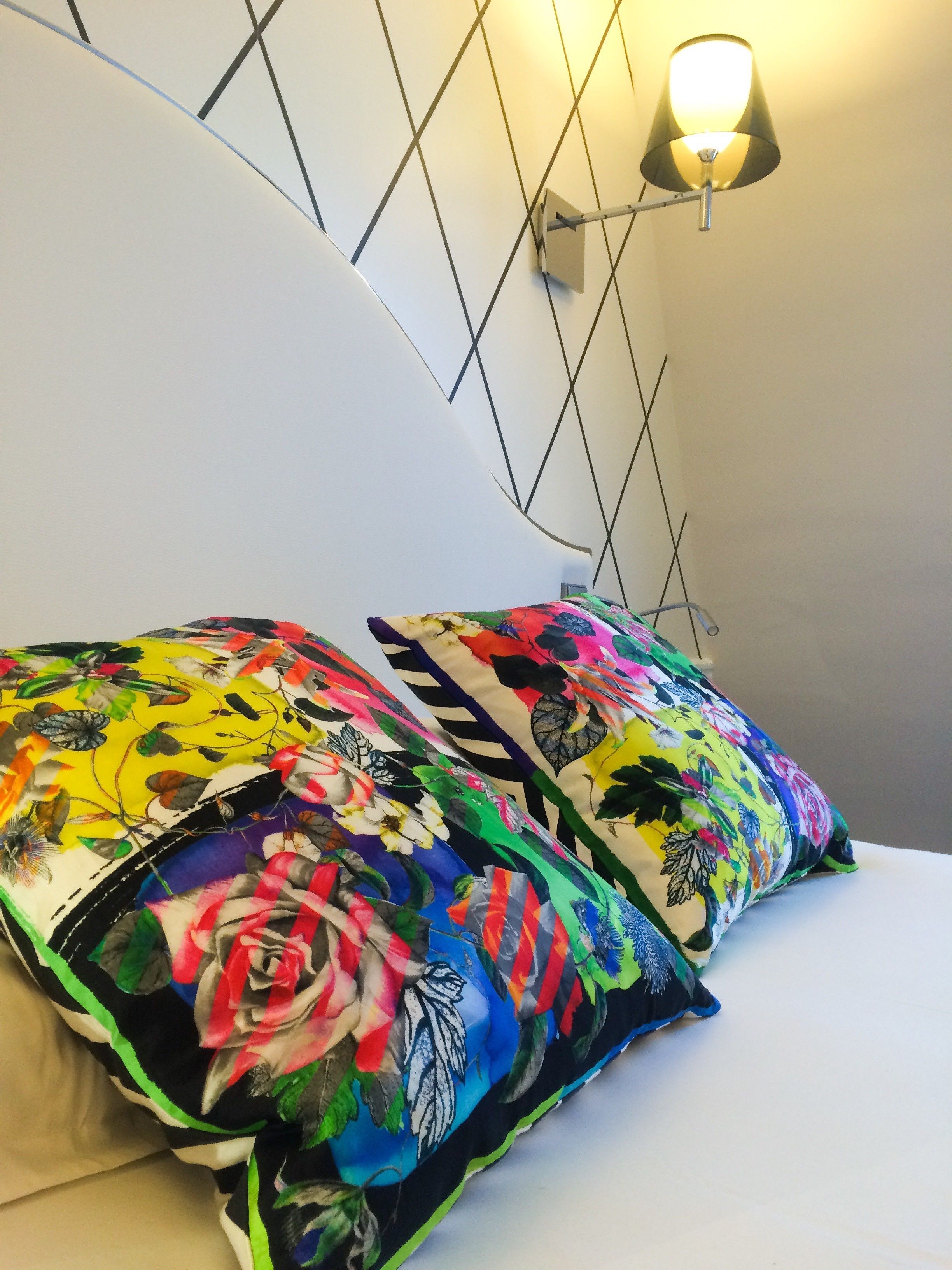 Un lit agrémenté de coussins aux motifs floraux colorés et d’une applique murale.