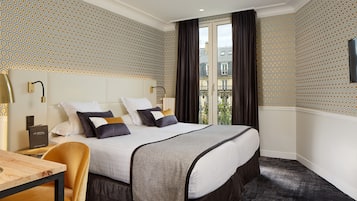 Une chambre d’hôtel avec un grand lit, un bureau et une vue sur la ville par la fenêtre.
