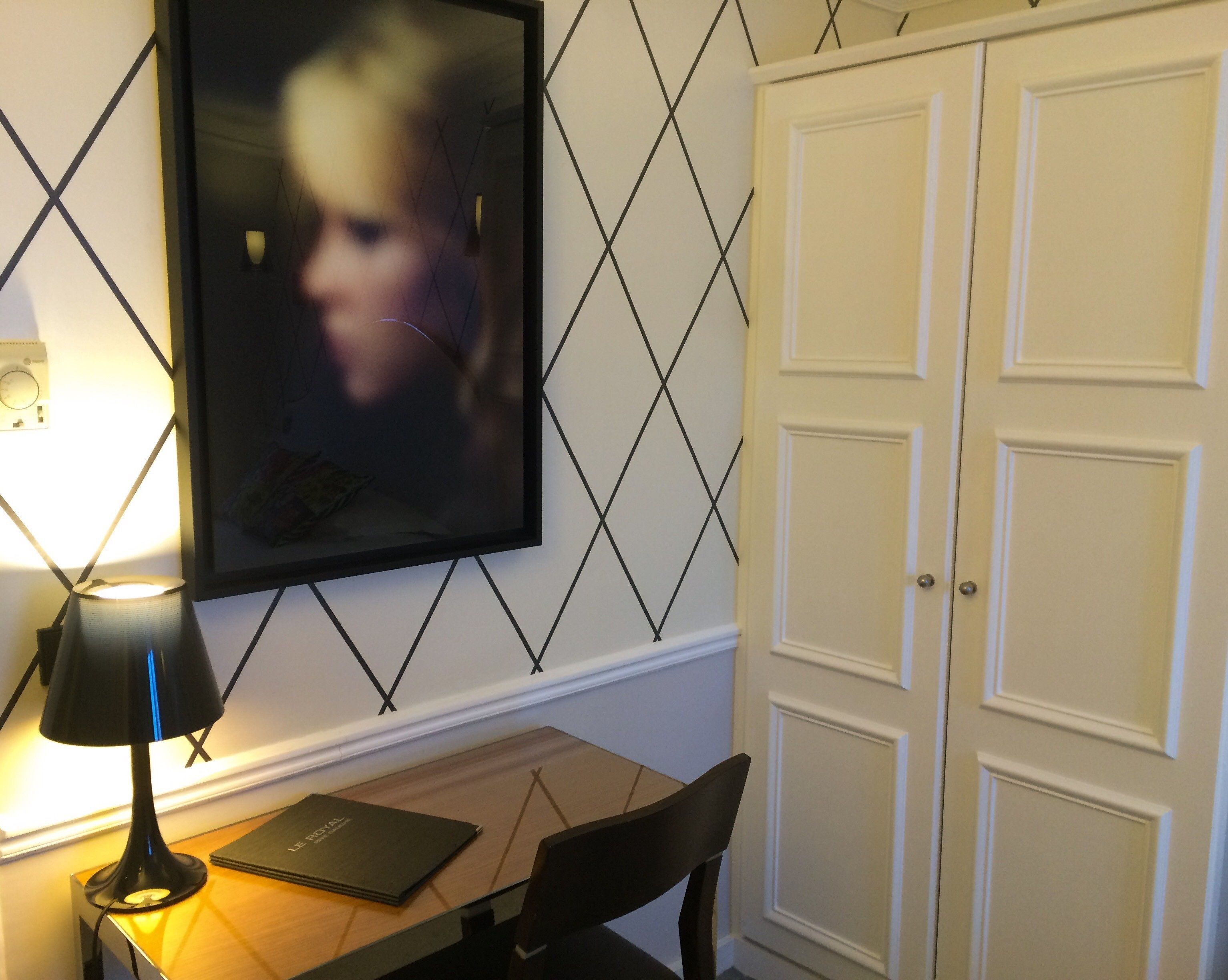 Quarto com escrivaninha, cadeira, quadro e guarda-roupa.