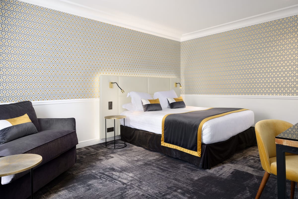 Ein Hotelzimmer mit einem großen Bett, einer Schlafcouch und einem kleinen Tisch.