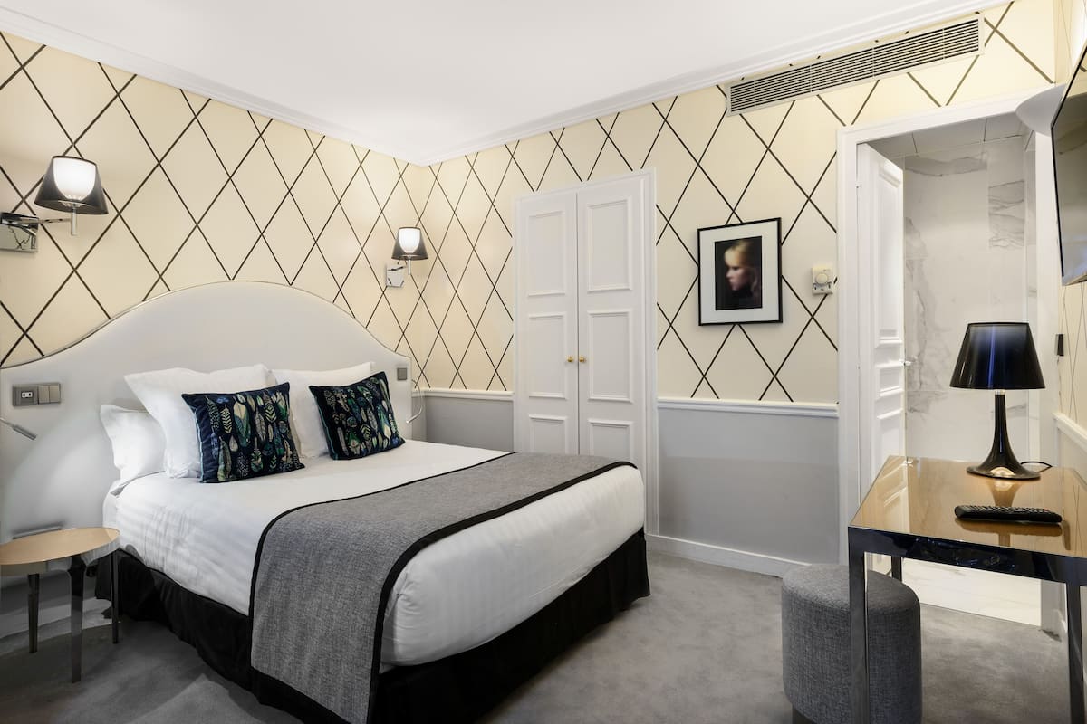 Ein ordentlich eingerichtetes Schlafzimmer mit Bett, Nachttischen, Schreibtisch und Stuhl.