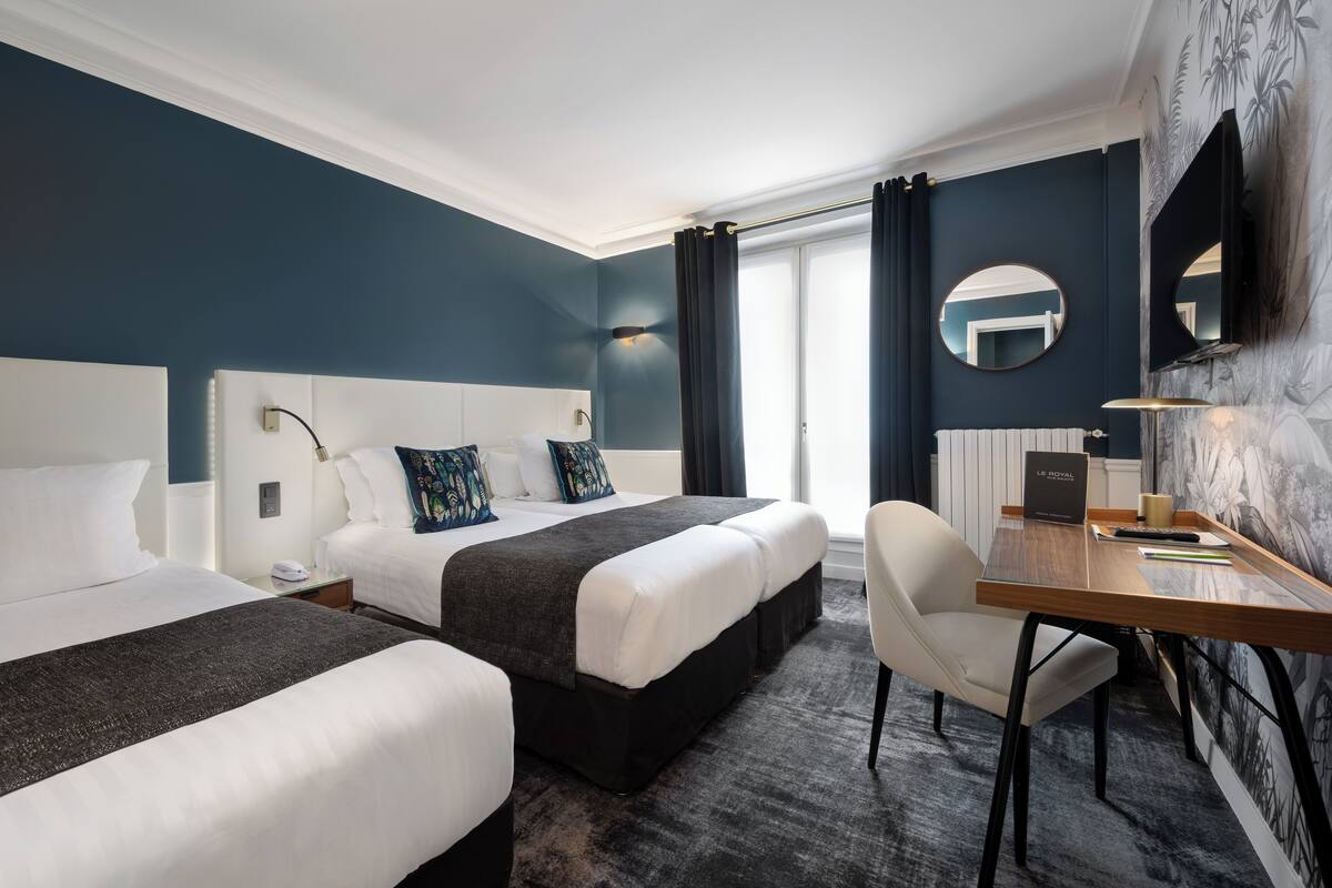 Ein Hotelzimmer mit zwei Betten, einem Schreibtisch und einem Stuhl.