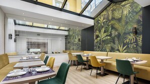 A modern dining area with tables, chairs, and a yellow sofa. - Hôtel Le Royal (Paris)