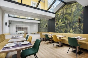 Un comedor moderno con mesas, sillas y un sofá amarillo.