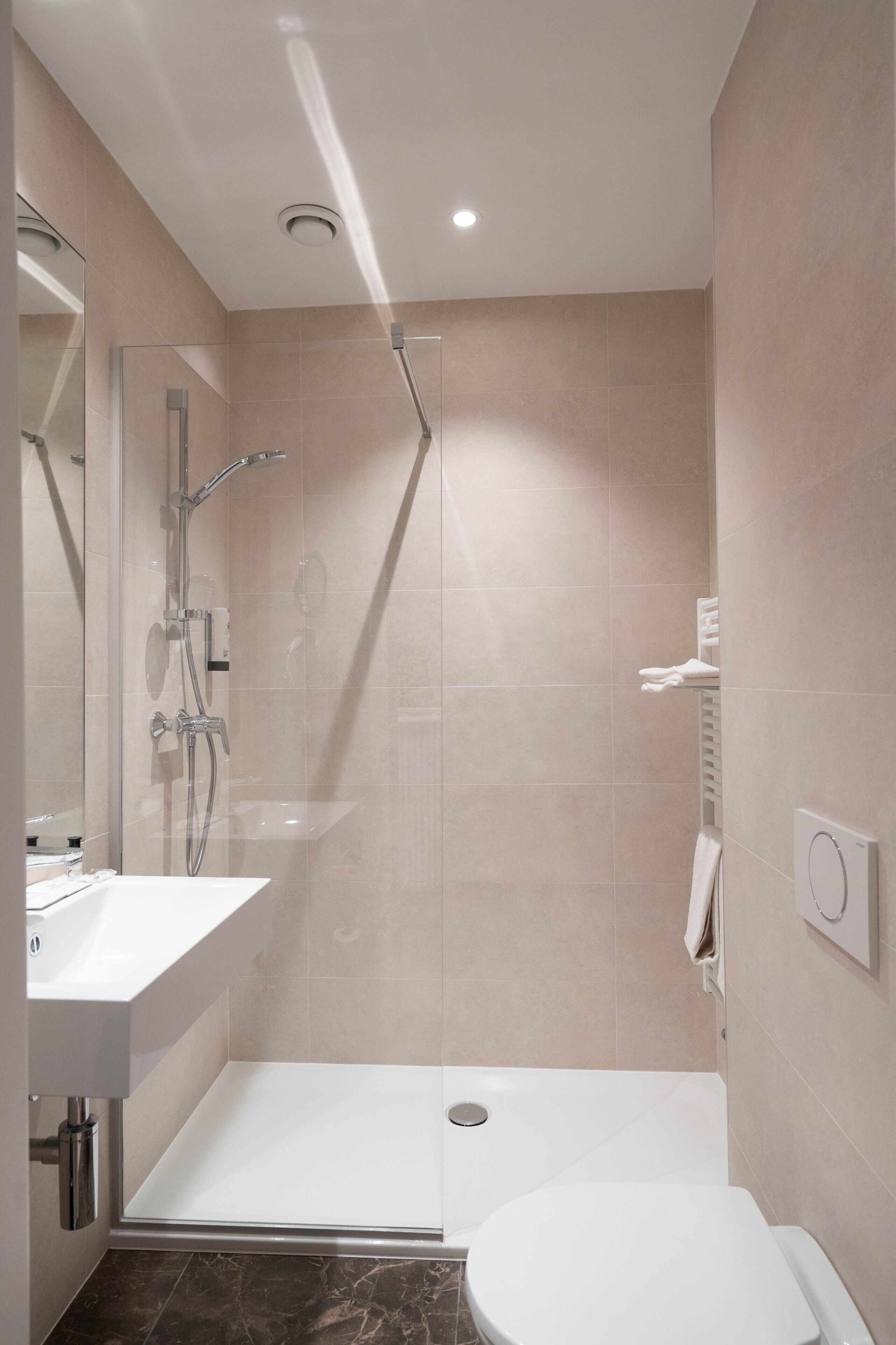Un baño moderno con ducha de vidrio, lavamanos blanco y retrete.