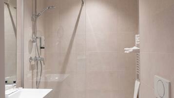 Un baño moderno con ducha de vidrio, lavamanos blanco y retrete.
