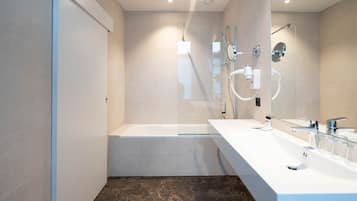 Un baño moderno con bañera, ducha y tocador con espejo.