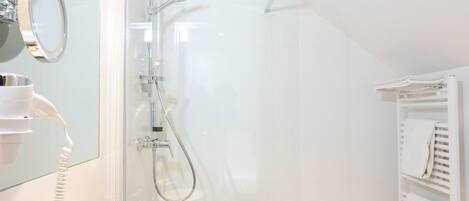 Un baño moderno con ducha envuelta en vidrio, un tocador con espejo y un perchero para toallas.