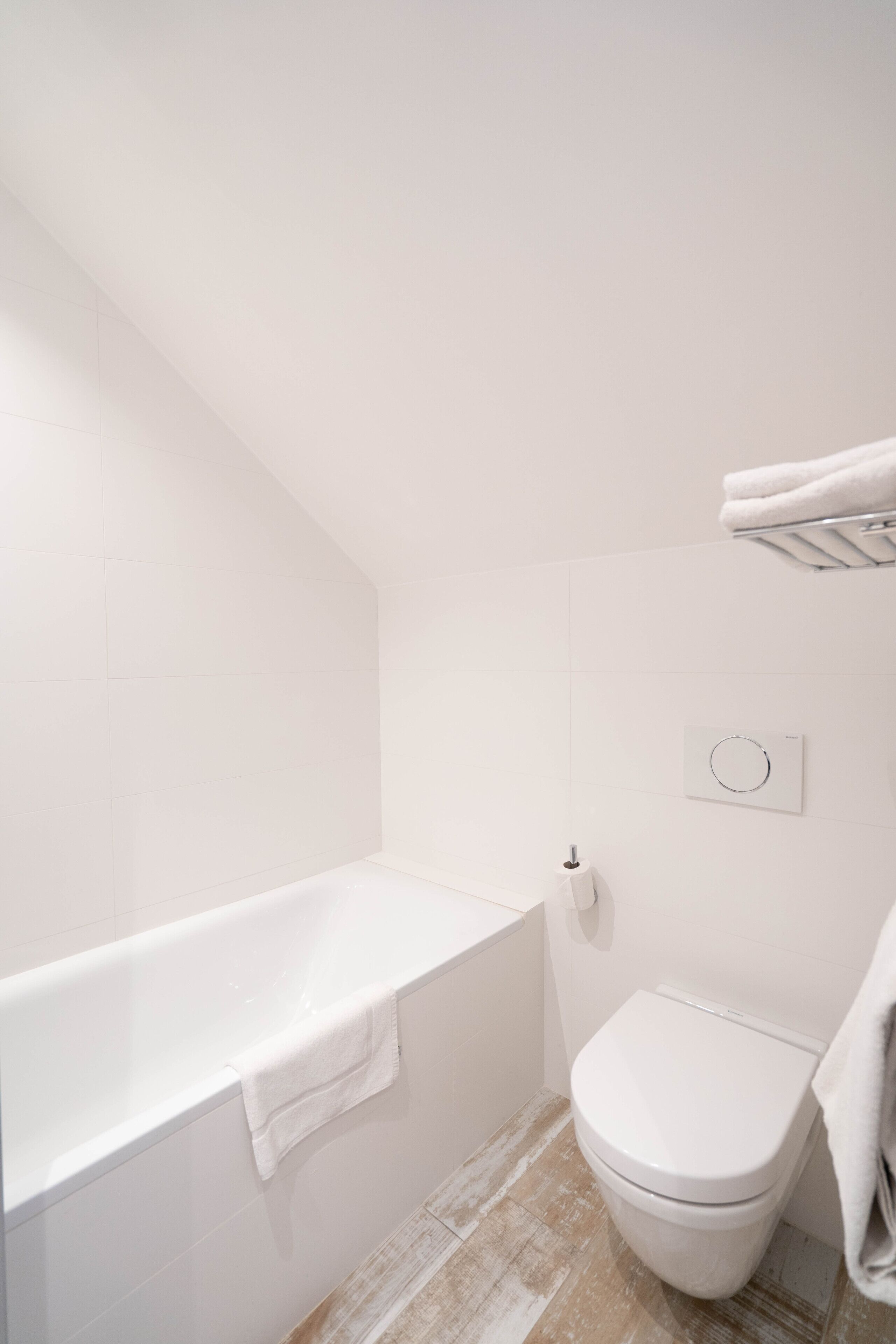 Ein modernes Badezimmer mit Badewanne, Toilette und Handtuchhalter.