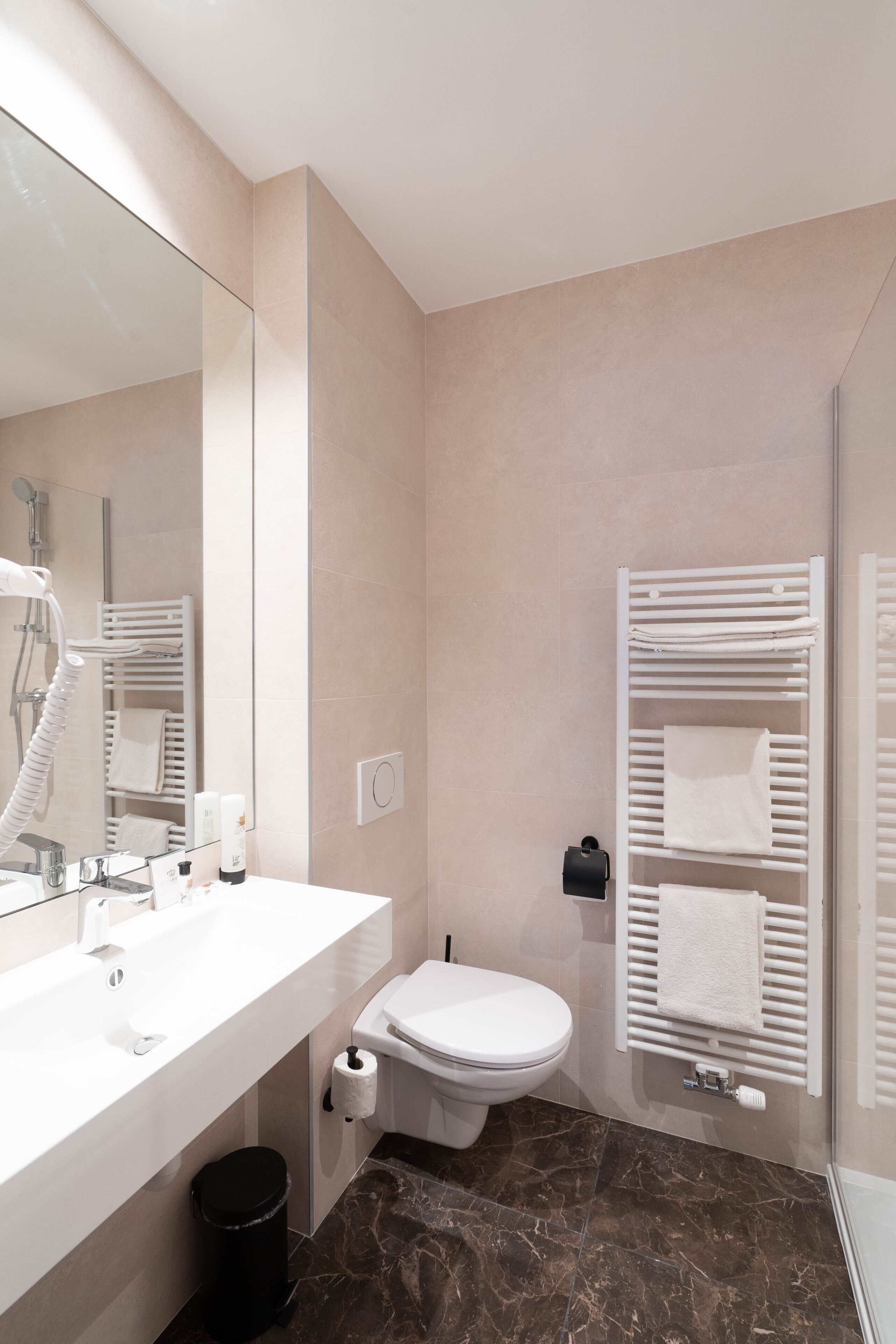 A modern bathroom with a white sink, toilet, and a glass shower enclosure.
