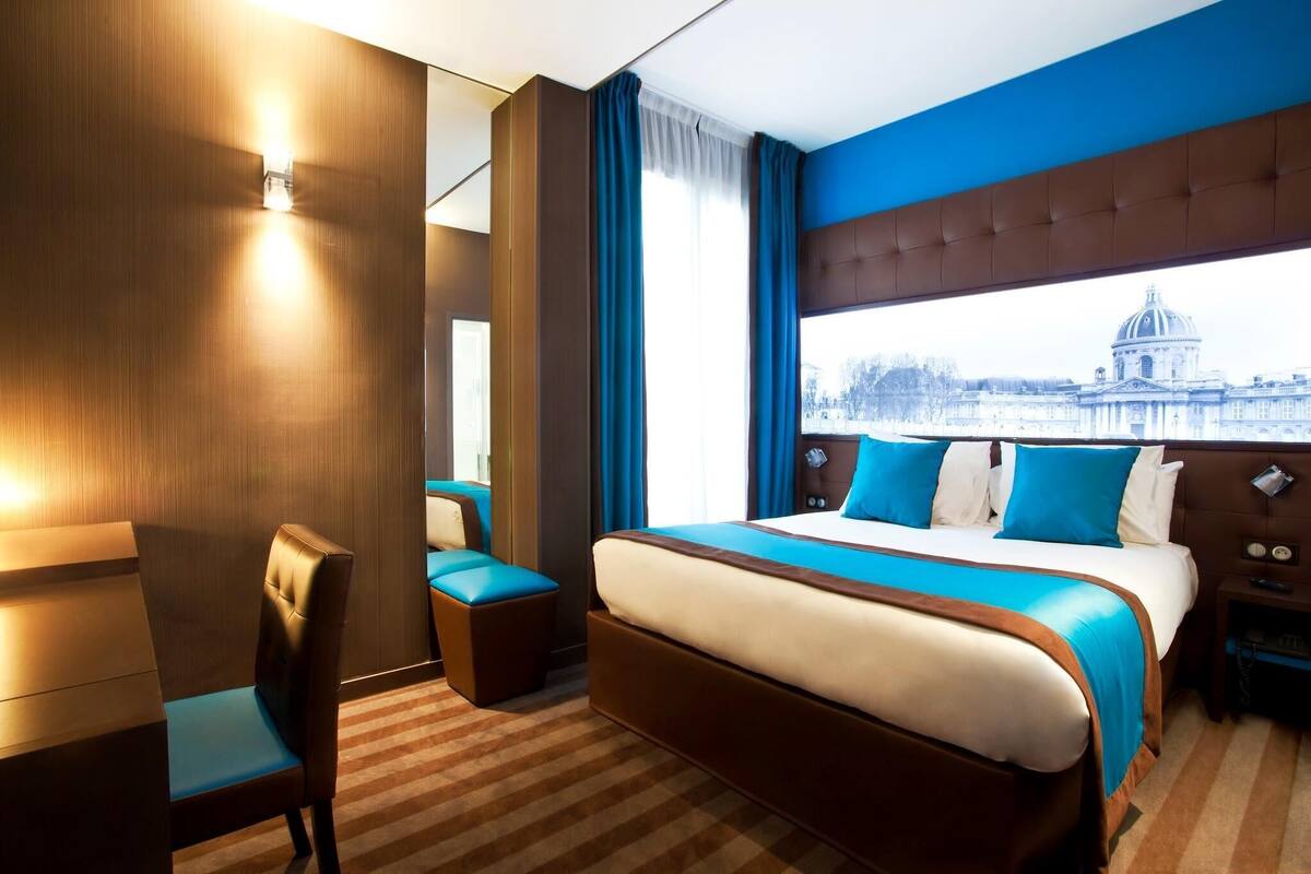 Una habitación de hotel con una cama grande, zona de estar y vistas a un edificio histórico.