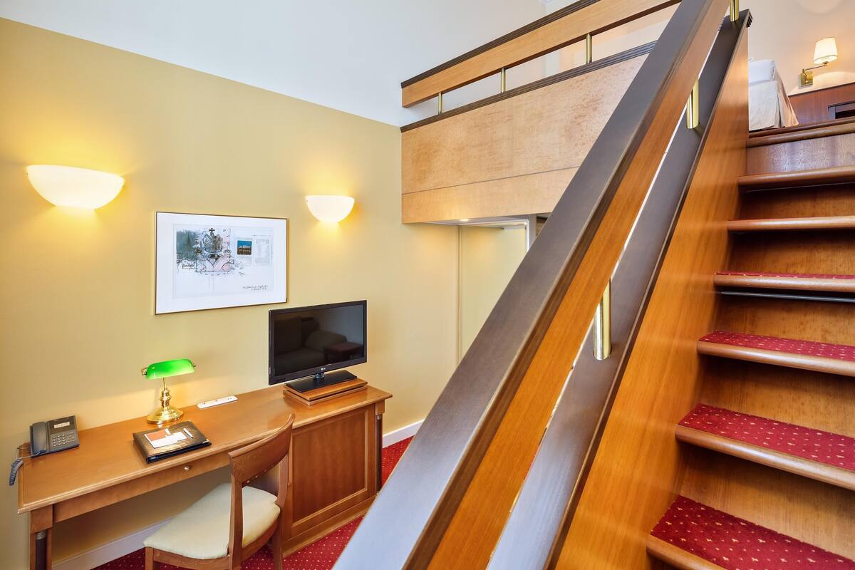 Una habitación de hotel con un escritorio de madera, una silla, un televisor y una cama.