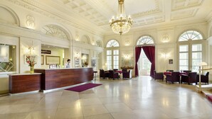 Een ruime lobby met een receptiebalie, zithoek en grote ramen.