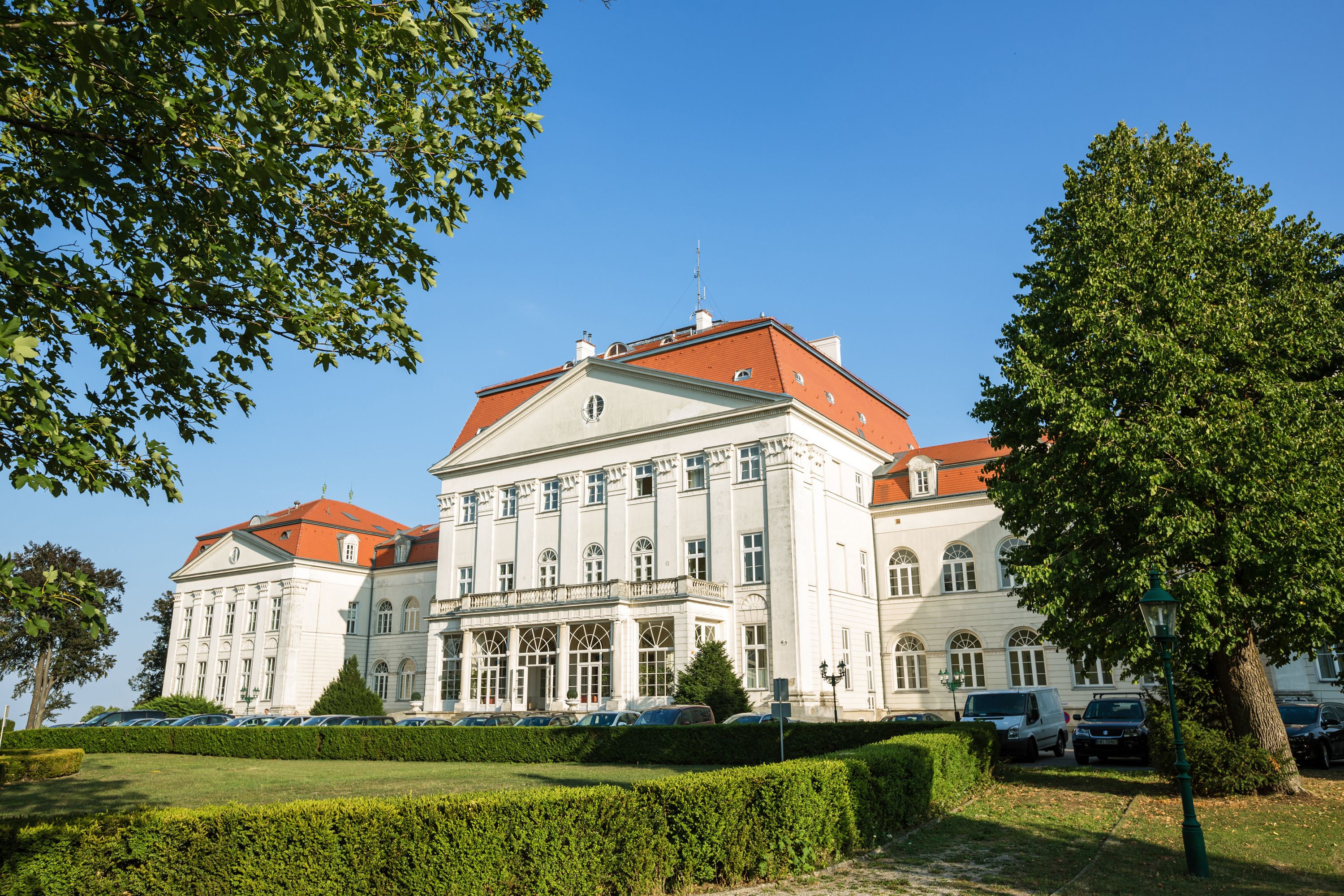 A large, historic building with a symmetrical facade, multiple windows, and a red roof.
