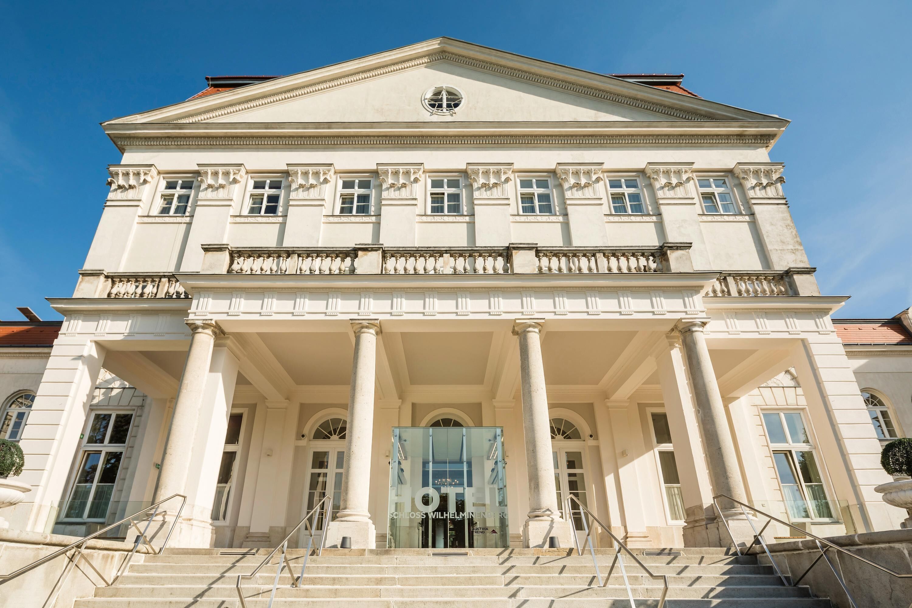 A grand building with a symmetrical facade, large columns, and a central entrance with glass doors.