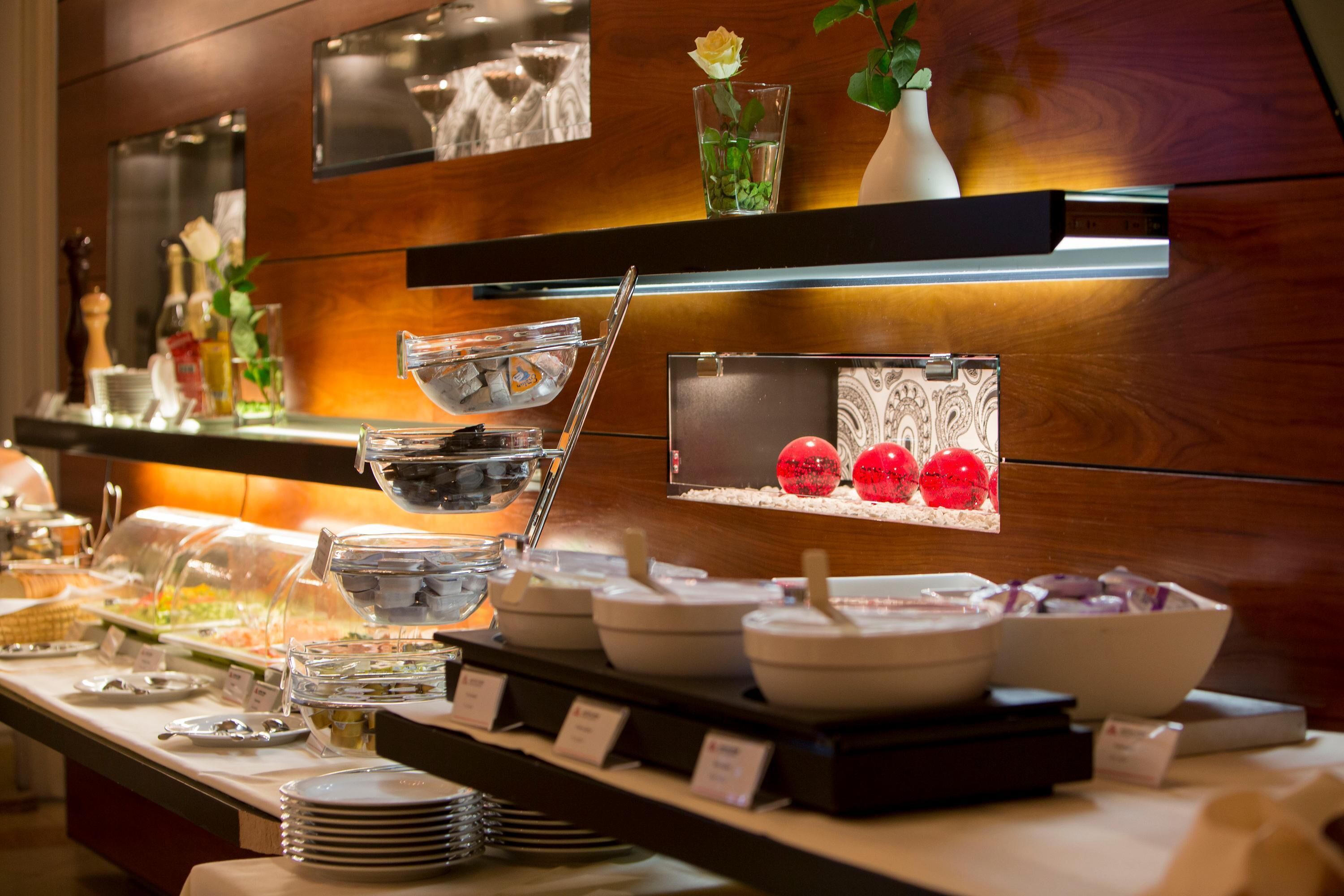 Un buffet con diversi piatti e una decorazione di ornamenti rossi.