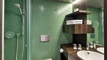 A modern bathroom with green tiled walls, a shower, a sink, and a mirror.