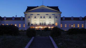 A grand building with a symmetrical facade, large windows, and a central entrance with a staircase leading up.