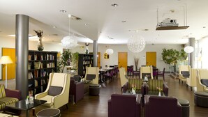 Een moderne zithoek met boekenkasten, comfortabele zitplaatsen en decoratieve verlichting.