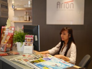 A reception desk with a computer, magazines, and a potted plant. - Arion Cityhotel Vienna (Vienna)