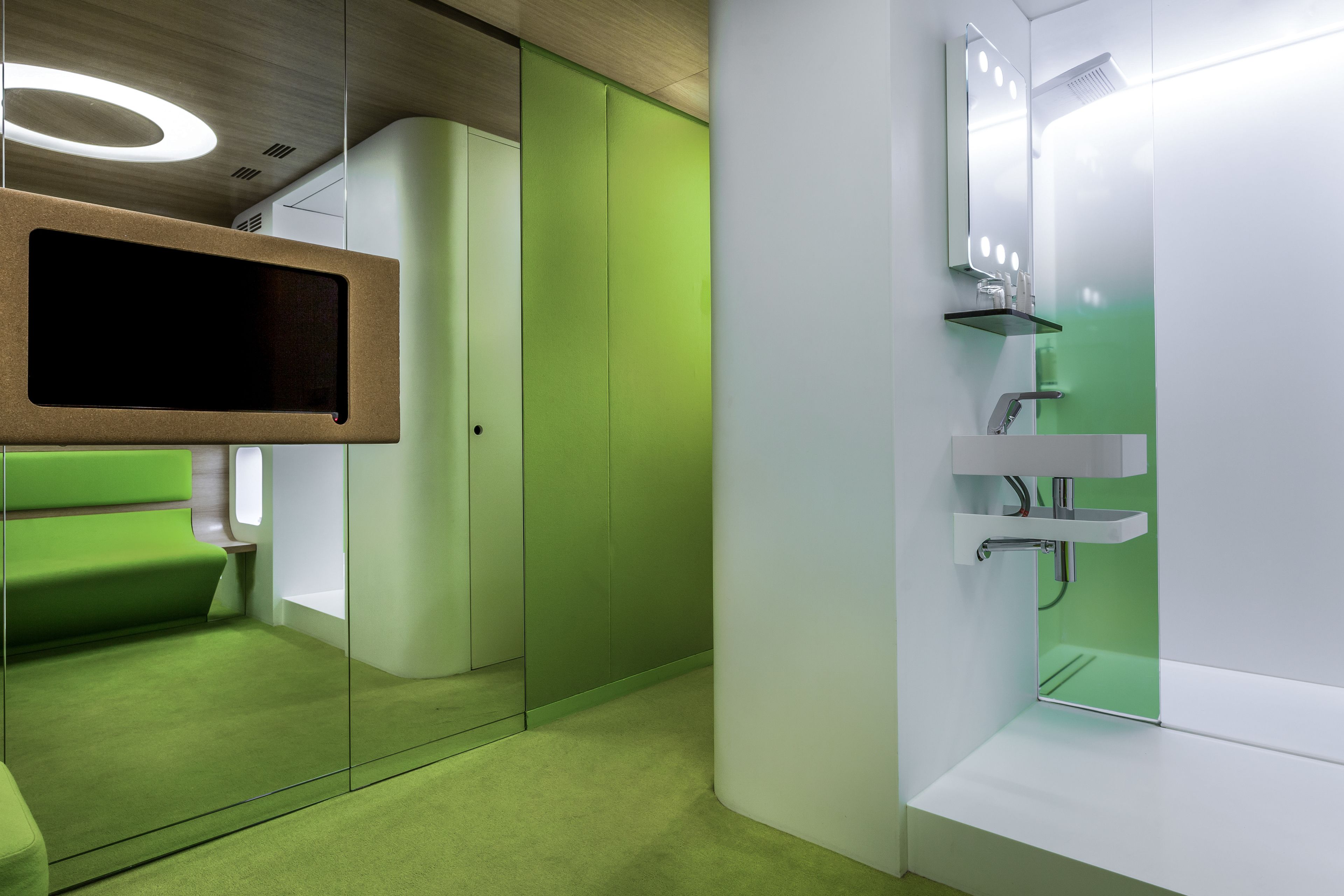 A modern bathroom with a green accent wall, a glass shower enclosure, and a vanity with a mirror.