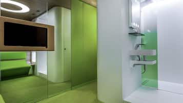 A modern bathroom with a green accent wall, a glass shower enclosure, and a vanity with a mirror.