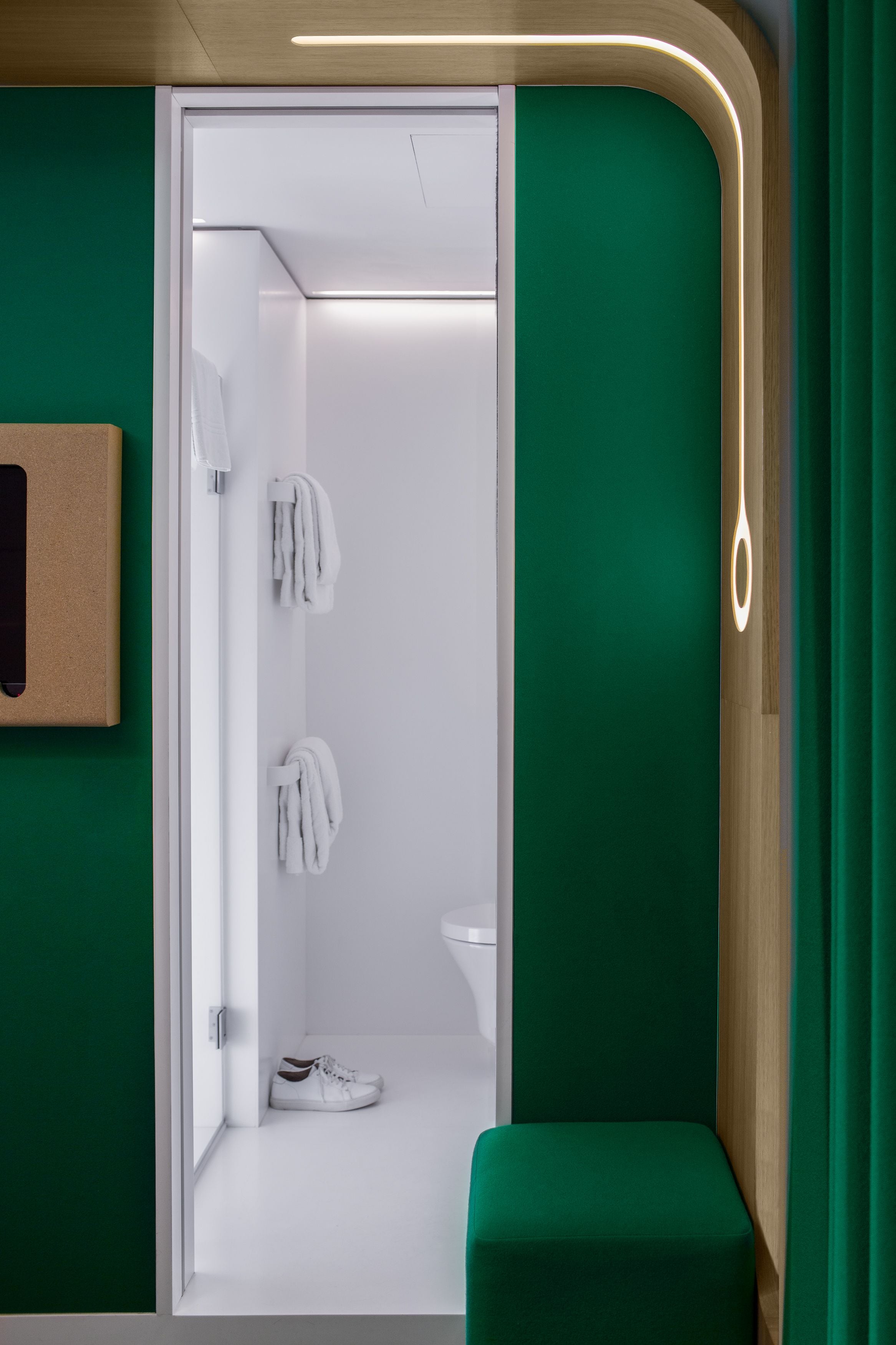 Ein modernes Badezimmer mit grüner Wand, einer hölzernen Bank und einem weißen Waschbecken.