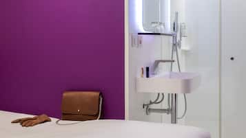 A modern bathroom with a purple wall, a white sink, and a brown handbag on the floor.