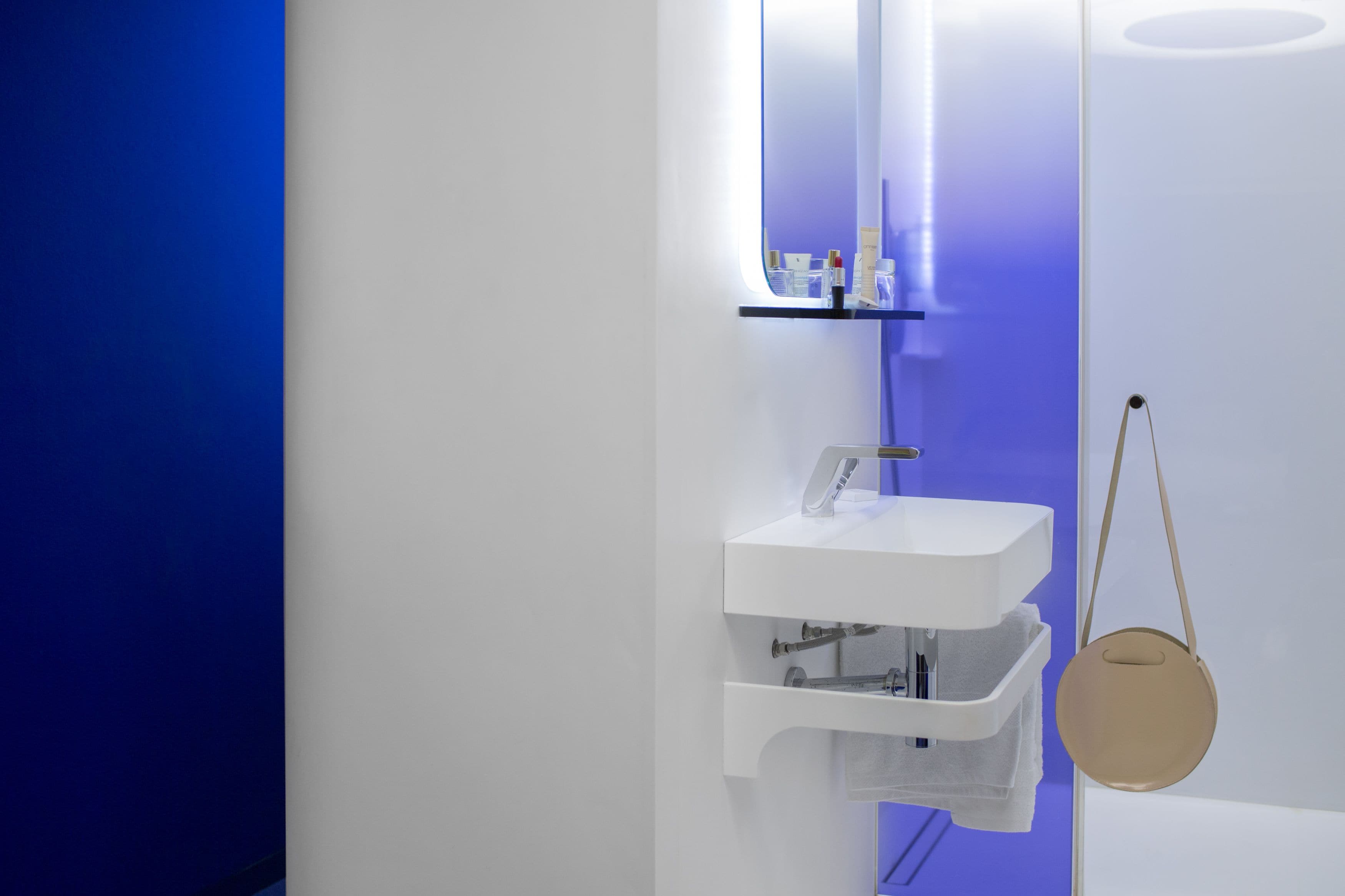 A modern bathroom with a white sink, a mirror, and a towel rack.