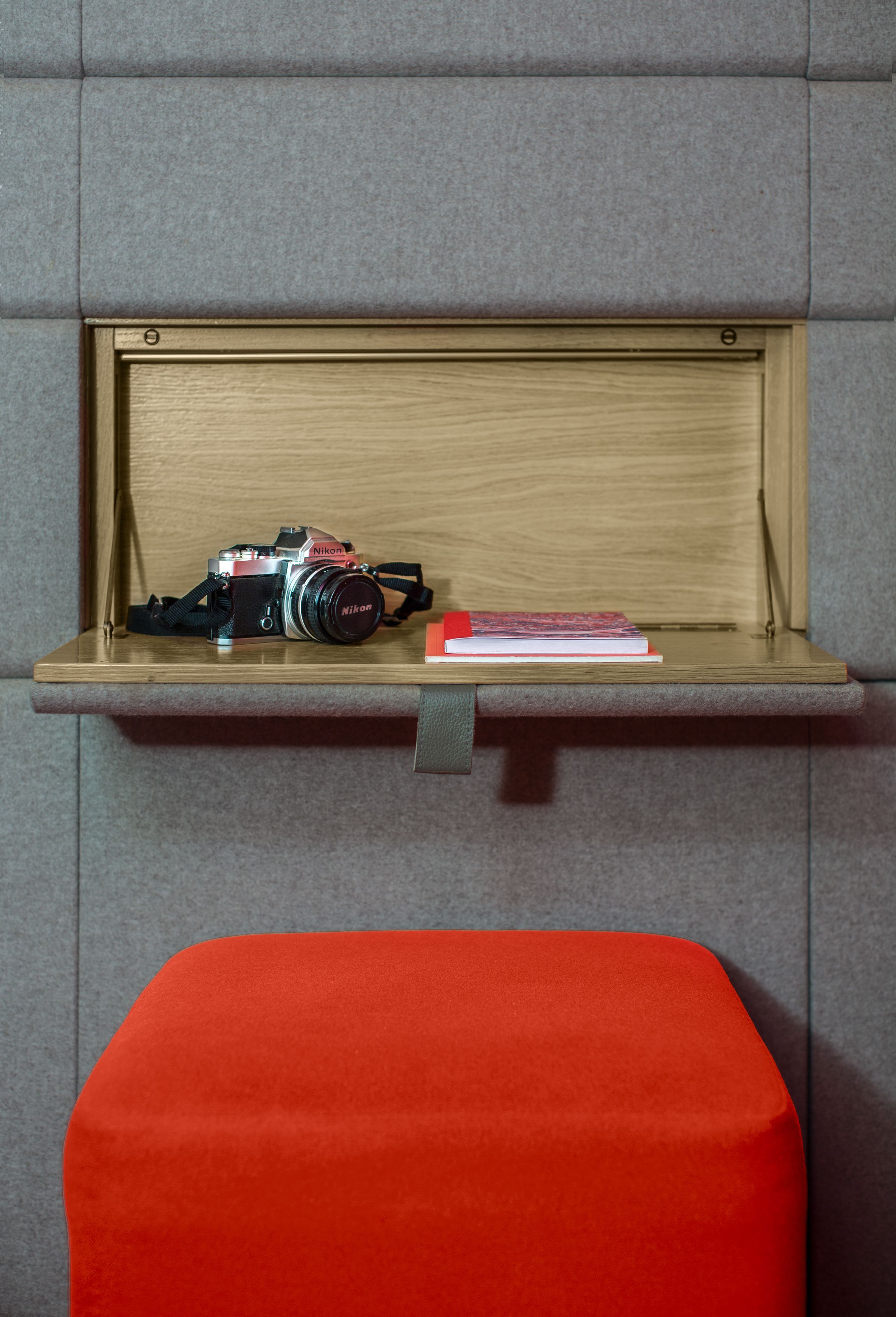 A wooden shelf with a camera and a book.