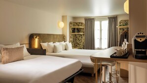 Habitación de hotel con dos camas, un escritorio con cafetera y una ventana con cortinas.