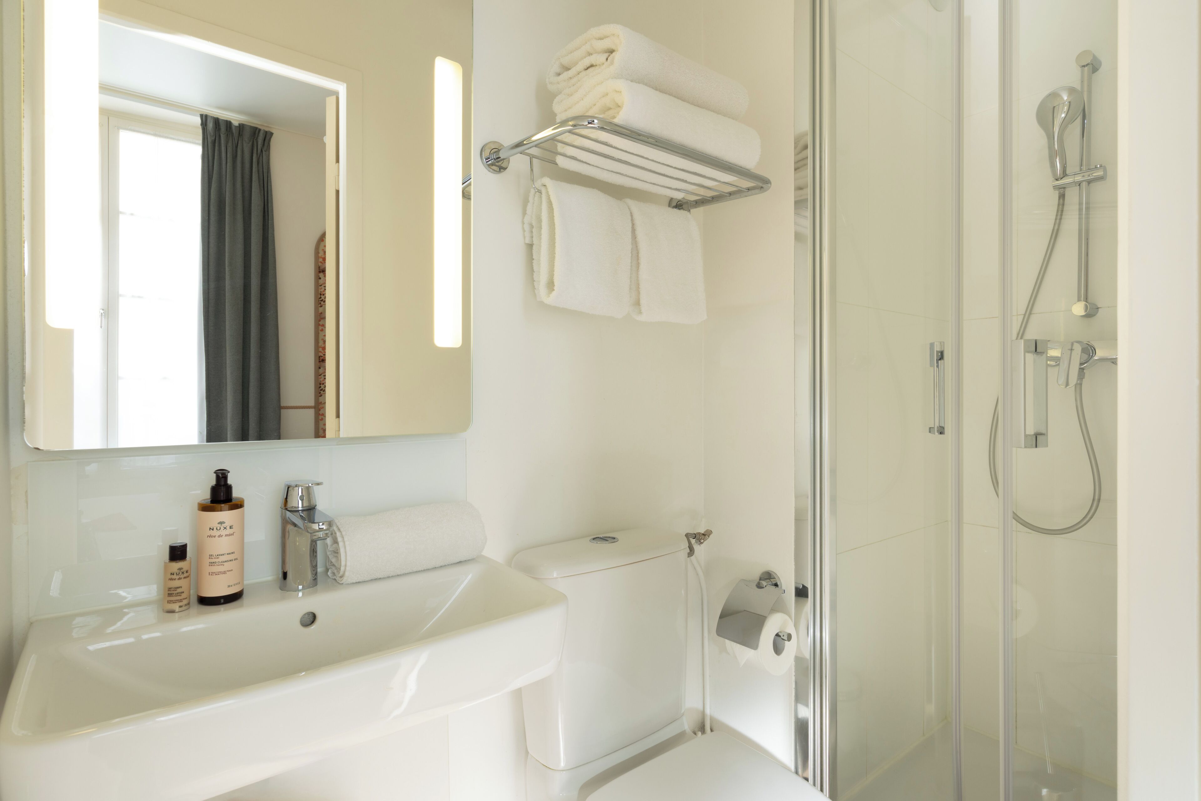 A bathroom with a sink, toilet, shower, and towel rack.