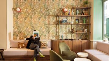 Une pièce avec un papier peint à motifs, une bibliothèque, un canapé et un fauteuil.
